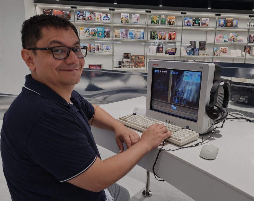 Leandro Junes, smiling at the camera, seated at a vintage Compaq desktop computer.